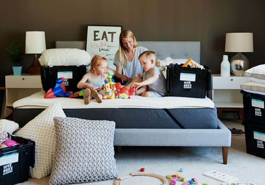 woman with children sitting on a bed around boxes