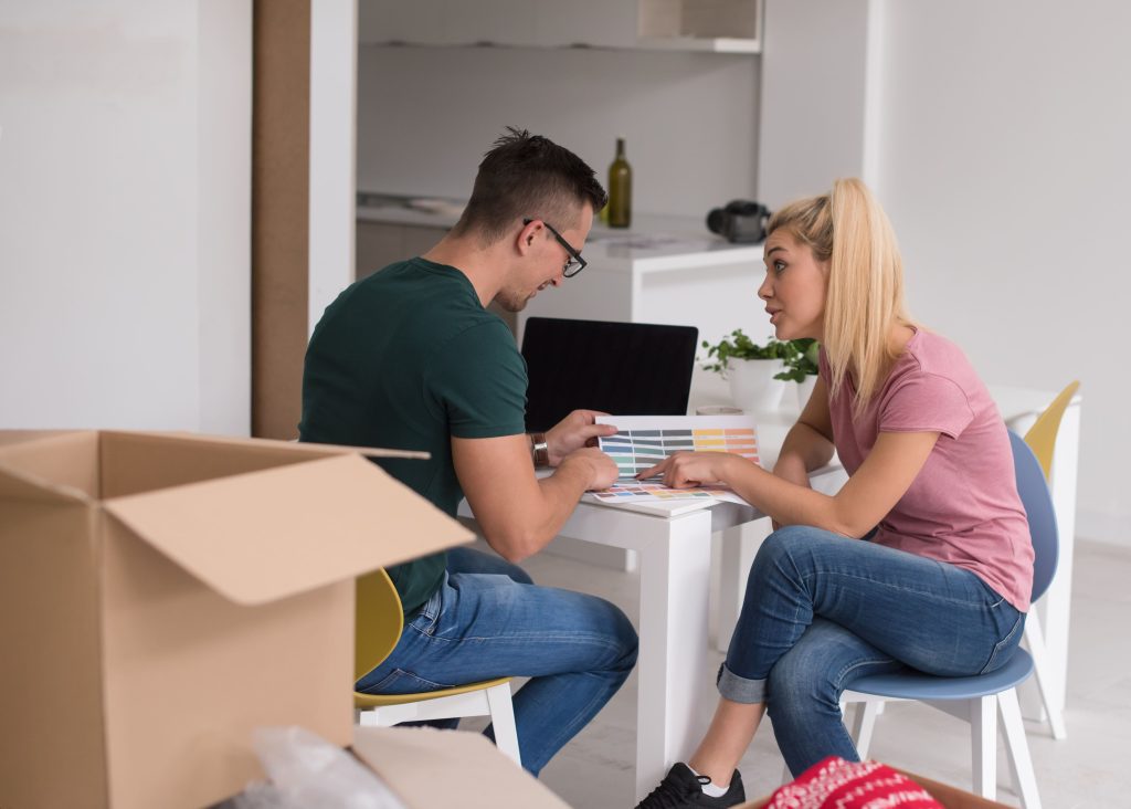 young couple, roommates, sitting in their new apartment, with boxes around them_roomates in Nashville tn