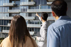 suited man pointing up, and showing something to a couple_nashville apartment finders